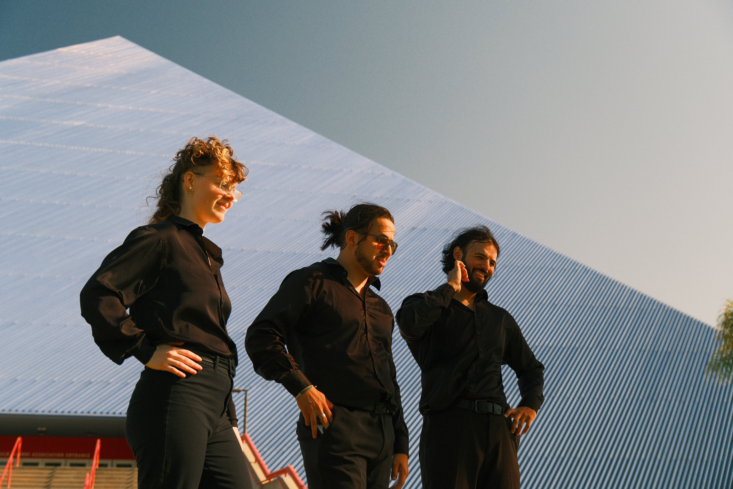 Three figures standing before a blue pyramid