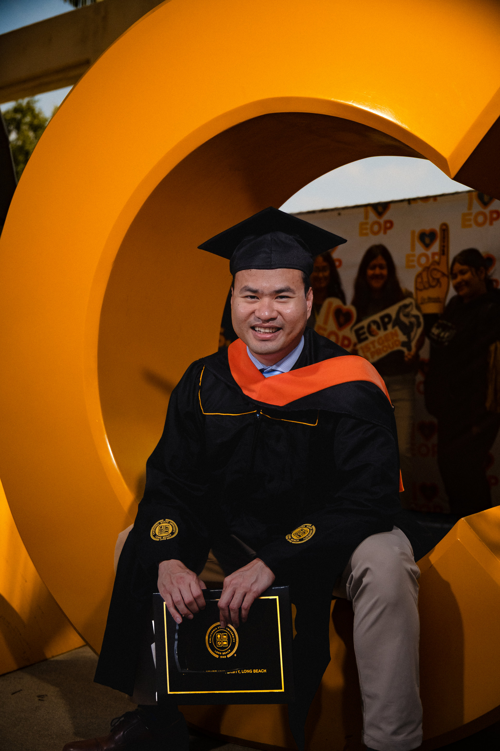 Graduate smiling while sitting in giant letter